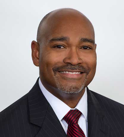 A man in a suit and tie smiling for the camera.