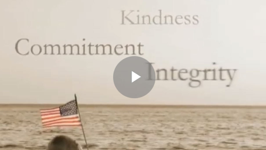 A person holding an american flag in front of the ocean.